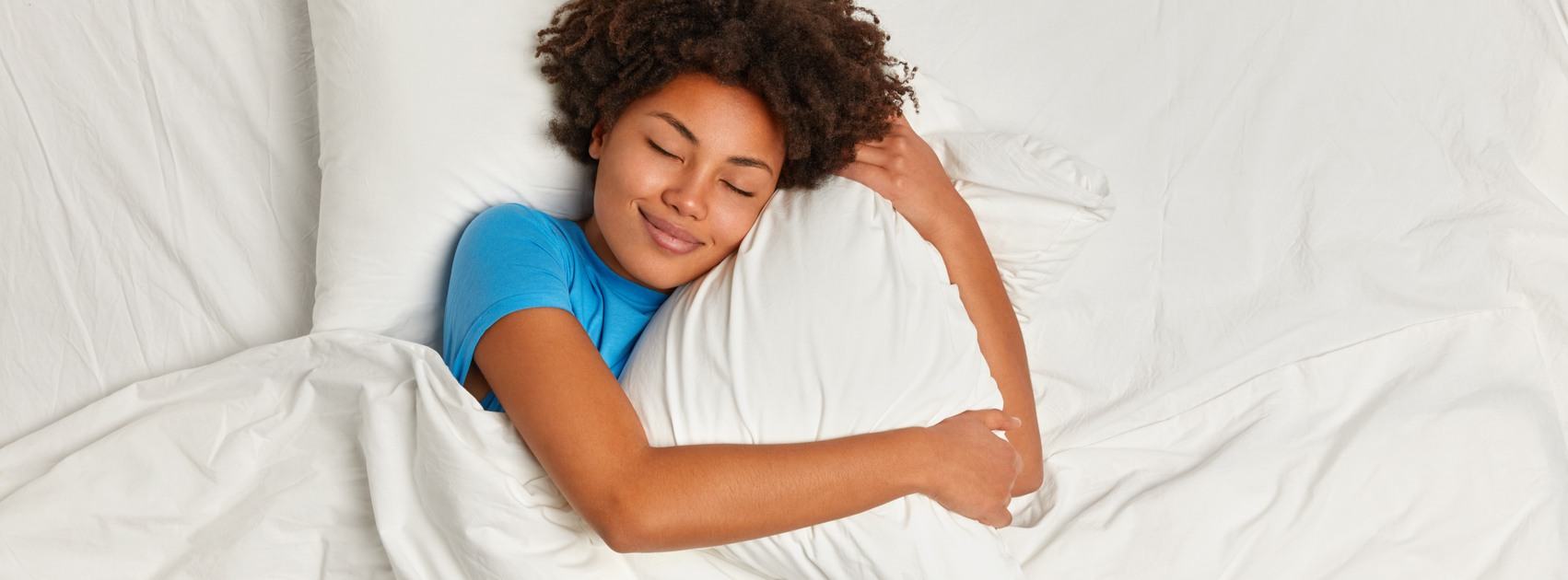 Woman sleeping soundly hugging one of her pillows 