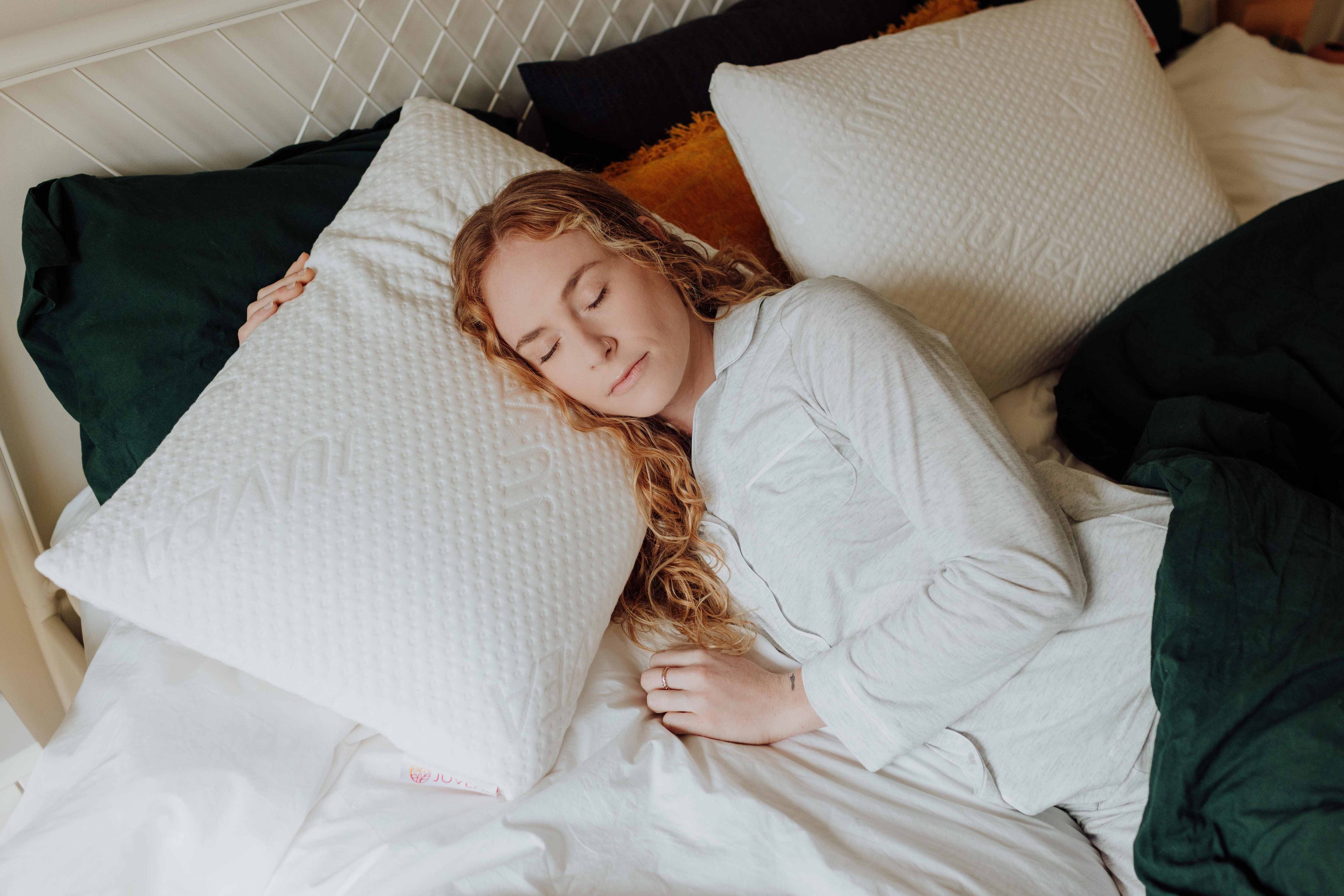 Woman sleeping on a bed with white pillows and green blanket